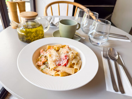Pasta dish with vegetables and cheese served with herbal tea in cafe. Dining moment symbolizing nutrition, lifestyle and gourmet cuisine culture.の写真素材