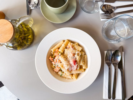 Overhead view of pasta with vegetables and grated cheese on white plate. Culinary scene symbolizing gourmet cuisine, nutrition and lifestyle dining.の写真素材