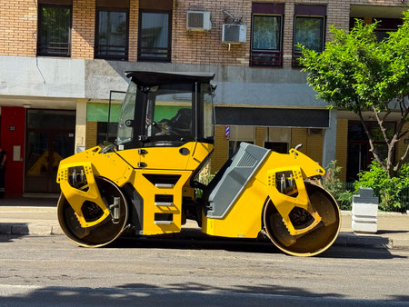 Yellow road roller closeup. Heavy construction, infrastructure repair, and industrial machinery in...