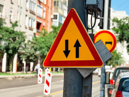 Traffic sign with two arrows indicating bidirectional vehicle movement on a city street. Guidance, regulation and transportation safety to ensure mobility, order and controlled infrastructure flow.の写真素材