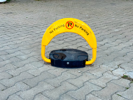Yellow no parking sign placed on pavement surface preventing unauthorized vehicle use of space. Regulation, prohibition and urban infrastructure symbolizing traffic control, order and restriction.の写真素材