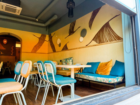 Interior of a cafe with colorful furniture, decorative pillows and painted bird motifs on the wall....