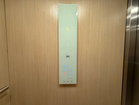 Modern elevator panel with illuminated floor buttons on wooden wall interior. Technology, transport...