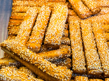 Golden sesame breadsticks stacked on a tray. Bakery, nutrition and healthy eating with traditional baked goods.の写真素材