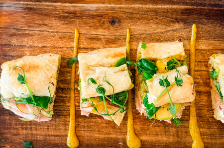 Sandwich portions with fresh vegetables on wooden tray. Culinary presentation, nutrition, and...