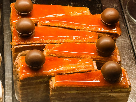 Rectangular layered pastries with glossy glaze and chocolate ball topping. Gourmet dessert, sweet...