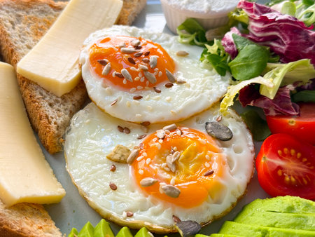 Closeup of fried eggs with seeds, toast, cheese, salad and avocado. Protein, health and fresh breakfast.の写真素材
