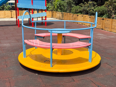 Colorful playground carousel with benches. Childhood, recreation, and outdoor fun in summer.