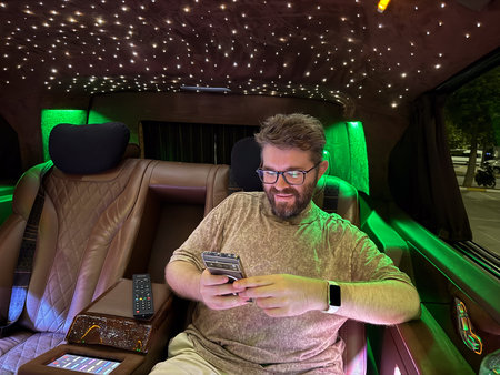 Man looking at phone inside luxury illuminated vehicle. Technology, relaxation and digital lifestyle...