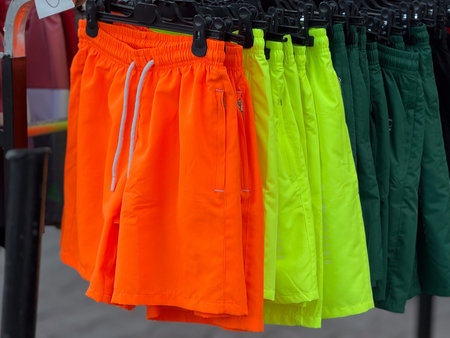 Clothing rack with colorful shorts displayed in street market. Retail, shopping, and fashion concept in outdoor urban commerce environment.の写真素材