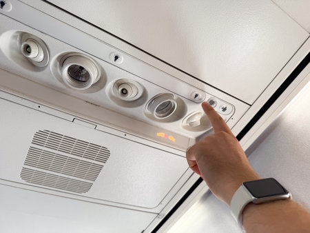 Airplane passenger pressing the flight attendant light button. Communication, service, and...