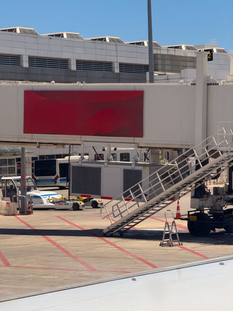 An airport ground view with a mobile stair connected to the gate area and service vehicles nearby. Infrastructure, aviation, and the preparation processes for boarding passengers.の写真素材