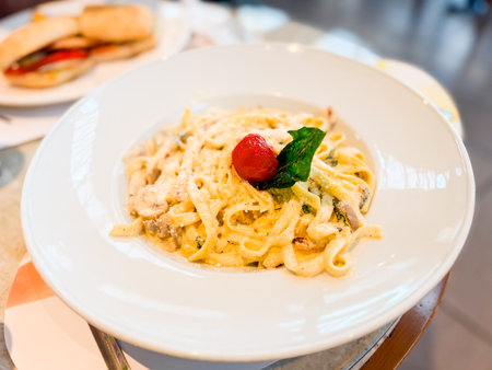 Plate of pasta with parmesan, mushroom, and cherry tomato garnish. Cuisine, nutrition, and lifestyle moments in restaurant dining culture.の写真素材