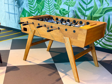 Wooden table football game set up in a lounge area for entertainment. Recreation, competition, and...