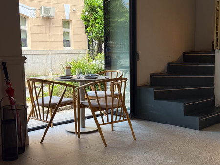 A wooden dining table with chairs and glassware stands by a window in a cafe. Hospitality,...