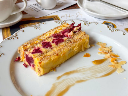 Cherry layered cake with almond topping served on decorated plate in cafe setting. Sweet dessert, gastronomy, and modern dining experience representing indulgence, lifestyle, and culinary presentation.の写真素材