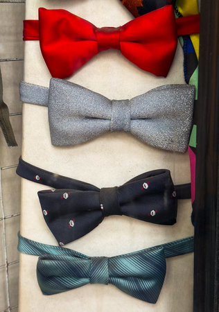Set of colorful bowties in red, silver, black, and green displayed in store. Fashion, menswear, and accessory variety for formal occasions and stylish wardrobe.の写真素材
