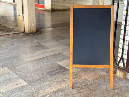 Wooden chalkboard sign with blank black surface placed outside urban building, copy space. Retail, commerce, and hospitality representing advertising, promotion, and communication of service.の写真素材