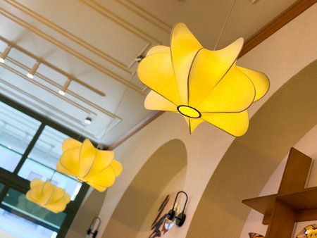 Yellow decorative ceiling lamp with modern floral shape in cafe interior. Lighting, design, and...