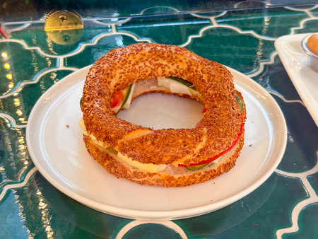 Traditional Turkish simit with sesame seeds filled with cheese, tomato, and cucumber. Street food,...