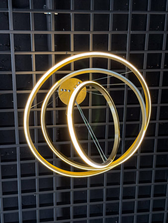 A glowing geometric chandelier with circular light rings. Innovation, technology, and modern interior lighting.の写真素材