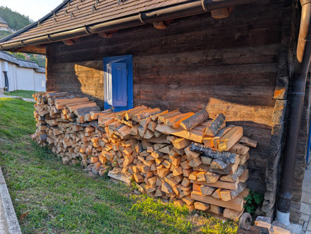 Piles of firewood near wooden house with colorful windows. Village lifestyle and architecture.の写真素材