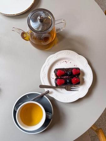 Top view of tea and chocolate dessert with berries on a table. Cozy pause, relaxation and comfort in cafe life.の写真素材