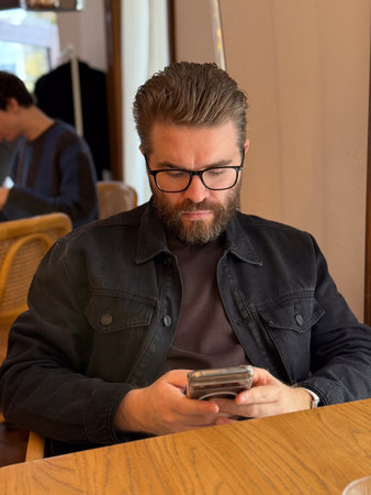 Man sitting in cafe looking at phone. Focus, calmness and everyday routine in modern lifestyle.