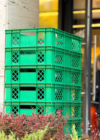 Stack of green plastic crates near store entrance. Urban storage, retail logistics and everyday...