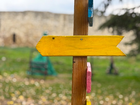 Yellow wooden arrow sign on post outdoors. Symbol of direction, guidance and creative navigation. Copy space and empty spaceの写真素材