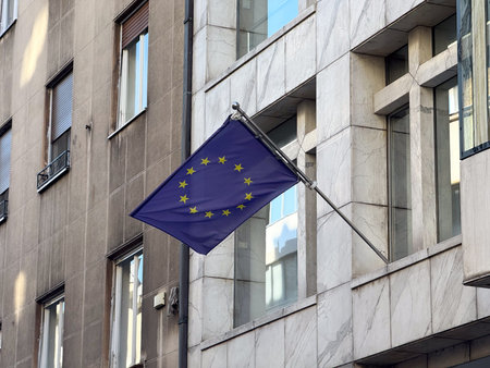 European Union flag waving on city building. Symbol of unity, diplomacy and European identity.の写真素材
