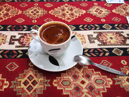 Turkish coffee cup resting on colorful textile tablecloth. Tradition, ritual and sensory pleasure of authentic Istanbul cafe culture.の写真素材