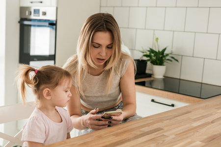 Mother and daughter spending time together at home. Family connection, parenting, communication, and everyday life in a cozy domestic interior.の写真素材