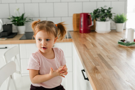 Preschool girl talking animatedly in the kitchen, copy space. Communication, self-expression, and emotional development in the safe and familiar space of home.の写真素材