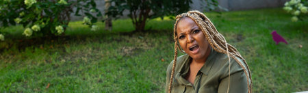 Banner confused african american woman sitting in park with puzzled expression. Copy space. Humor,...