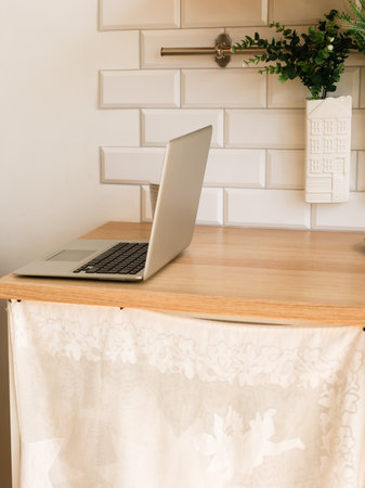 Laptop on wooden kitchen counter with green plants and ceramic decor. Minimalist workspace, calm lifestyle, and home aesthetic.の写真素材