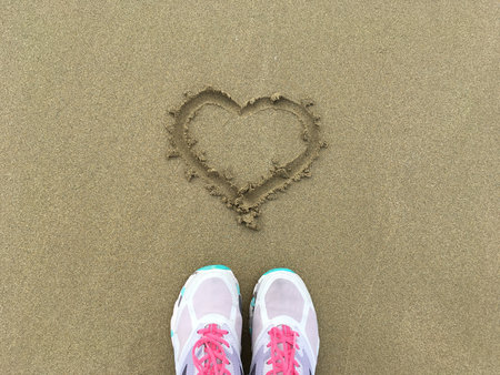 Heart symbol traced in sand by the sea. Expression of love, simplicity, and connection with nature and emotion.の写真素材
