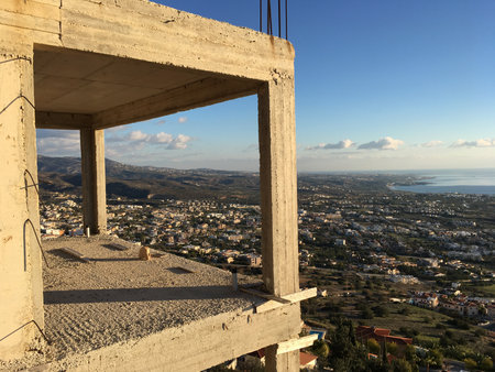 Unfinished concrete frame overlooking coastal valley. Progress, perspective, and transformation between creation and emptiness.の写真素材