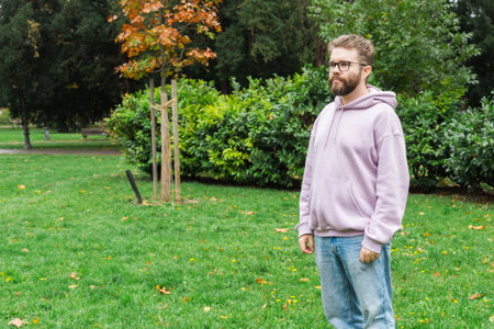 Man standing near autumn tree in park. Space and empty place for advertising. Simplicity, calm reflection and urban leisure.の写真素材