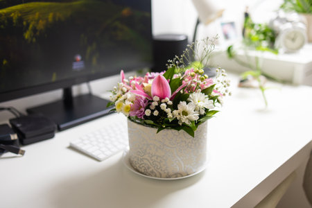 Flower arrangement on desk with computer monitor. Calm balance between work routine and home comfort.の写真素材