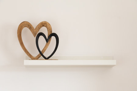 Wooden hearts on white shelf. Tenderness, simplicity, and emotional harmony in modern interior. Copy spaceの写真素材