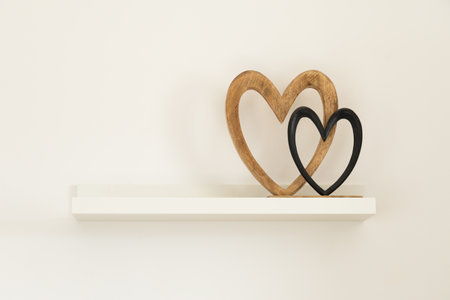 Wooden hearts on white shelf. Tenderness, simplicity, and emotional harmony in modern interior. Copy spaceの写真素材