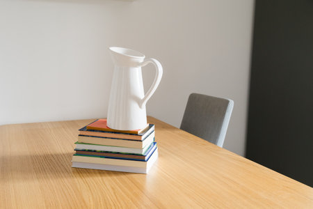 White jug on stack of books. Simplicity, knowledge, and artistic balance of modern home decor. Copy spaceの写真素材