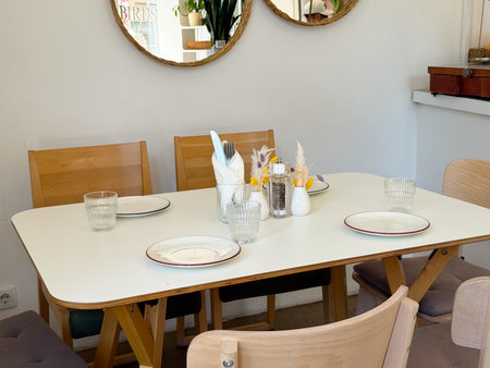 Cozy cafe table set with wooden chairs and minimalist decor. Warm atmosphere, hospitality, and Scandinavian interior design.の写真素材