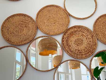 Round mirrors and woven wall decor in bright cafe. Natural materials, geometry, and cozy modern interior style.の写真素材