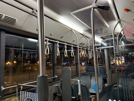 City bus interior with metal poles and empty seats. Night urban transport, routine, and everyday...
