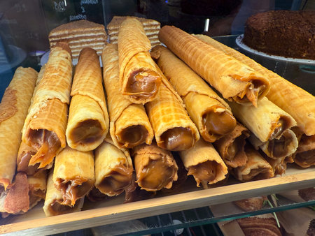 Waffle rolls filled with caramel cream on display. Confectionery production, dessert craftsmanship...