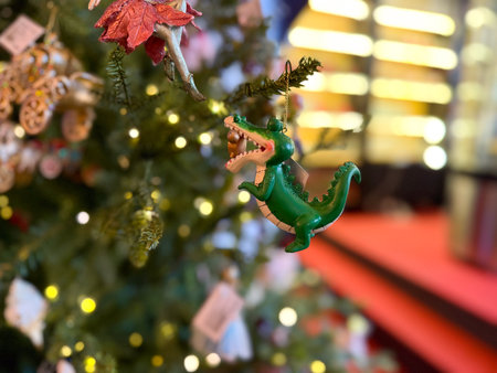 Green crocodile ornament hanging on a festive Christmas tree. Playful fantasy, whimsical storytelling and joyful seasonal charm creating magical holiday atmosphere and bright winter celebrationの写真素材