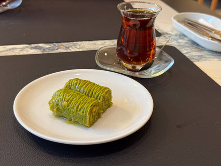 Pistachio baklava dessert on white plate close-up. Cafe sweetness, gourmet treat, green pastry...