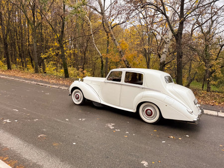 White vintage car driving on wet city road. Retro transport, classic elegance and timeless...